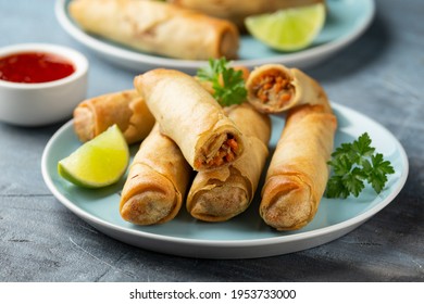 Fried spring rolls with sweet chili sauce and lime on plate - Shutterstock ID 1953733000