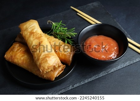 Fried spring rolls with sweet chili sauce on dark background. Asian cuisine.