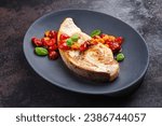 Fried swordfish steak with tomatoes and paprika served as close-up on a design plate 