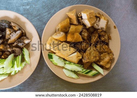 Fried tofu snack food served with raw cucumber slices and eaten with sweet and sour spicy sauce.