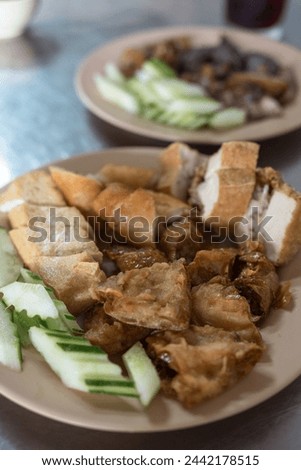 Fried tofu snack food served with raw cucumber slices and eaten with sweet and sour spicy sauce.