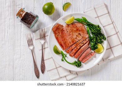 Fried Tuna Steak With Parboiled Broccolini And Lime On White Plate On White Textured Wooden Table, Overhead View, Flat Lay, Free Space