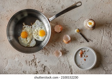 Fried two eggs in copper pan and hard boiled egg in stoneware egg cup on rough textured clay background. Healthy breakfast concept. - Powered by Shutterstock