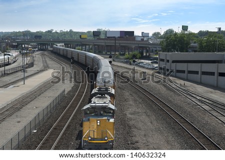 A frieght train approaching the camera in a winding urban stretch