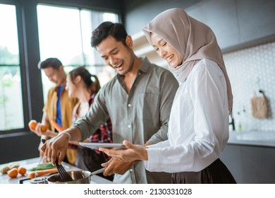 Friend Cooking Together In The Kitchen While Looking At Online Course From Tablet Pc