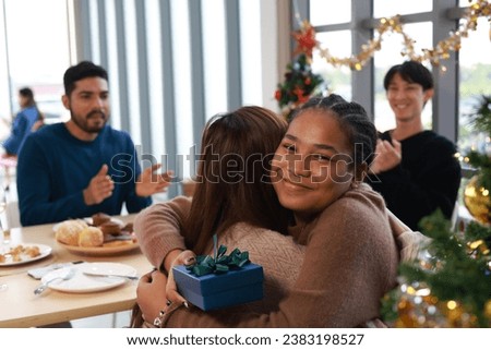 Friend giving a Christmas gift during a celebratory meal together