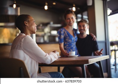 Friend interacting with happy couple while having coffee in restaurant - Shutterstock ID 637839703