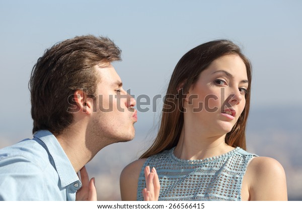 Friend zone concept with a man trying to kiss a woman\
and she rejecting him