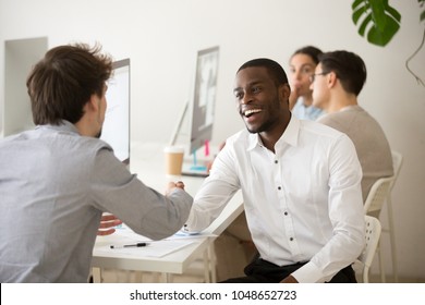 Friendly african advisor handshaking customer or colleague in office, smiling black and white entrepreneurs happy to make deal, excited diverse colleagues shake hands celebrating successful teamwork