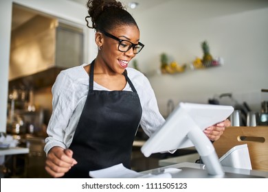 Friendly African American Shop Assistant Using Pos Terminal To Input Orders At Restaurant       