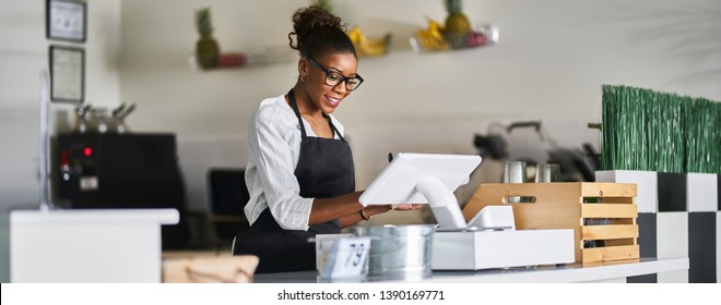 Friendly African American Shop Assistant Using Pos Terminal To Input Orders At Restaurant