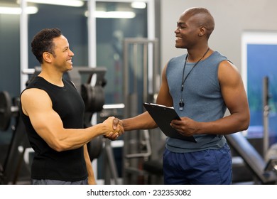 friendly african gym trainer handshaking with mid age client in gym - Powered by Shutterstock