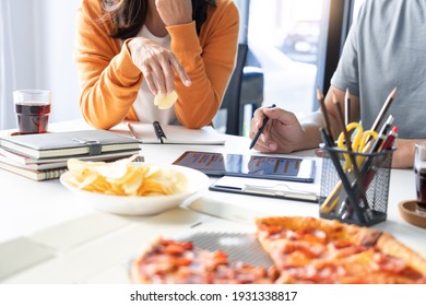 Friendly Asian Business Team Colleagues Eating Pizza And Potato Chips Together In Office Have Fun Talk Enjoy Corporate Party.