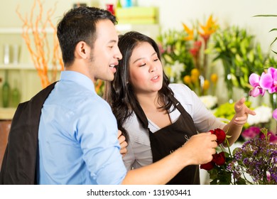 Friendly Asian Florist Or Saleswoman In A Flower Shop Advising A Customer