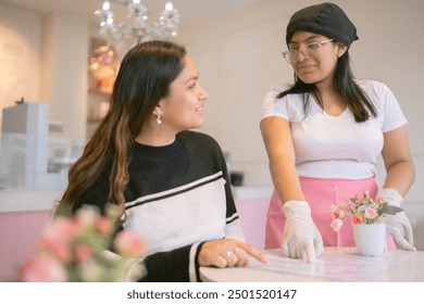 Friendly barista wearing gloves is explaining the menu to a customer in a coffee shop - Powered by Shutterstock