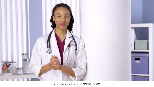 Friendly black woman doctor standing in office
