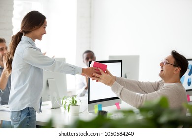 Friendly Business Team Congratulating Colleague Making Surprise Present, Smiling Woman Giving Excited Coworker Or Boss Gift Box, Employees Group Greeting Man Wishing Happy Birthday In Office Concept