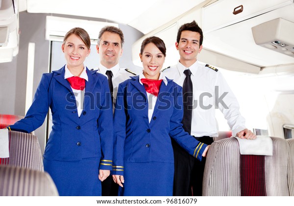 Friendly cabin crew in\
an airplane smiling