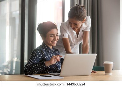 Friendly caucasian female mentor manager supervise indian intern secretary helping coworker with computer work instruct trainee give advice at office desk, apprentice, teamwork and mentoring concept - Shutterstock ID 1443633224