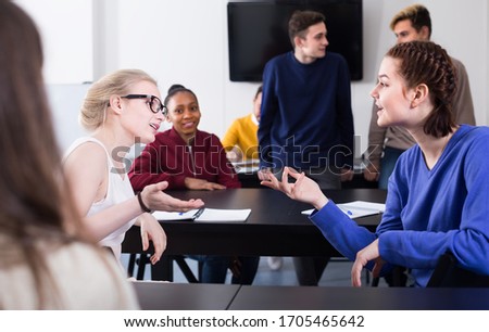 friendly classmates having animated talks at break between classes sits by the table