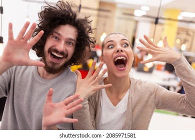 Friendly Colleagues Fooling Around In A Modern Coworking Office Space. Lovely Couple Making Funny Face Expressions.