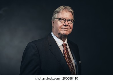 Friendly Confident Stylish Middle-aged Businessman Wearing Glasses Posing Against A Dark Background, Head And Shoulders Portrait