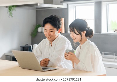 A friendly couple relaxing and chatting while looking at a computer (DINKS couple, relaxing)
					