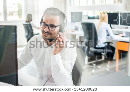 Friendly customer support agent with headset talking with client in call center.