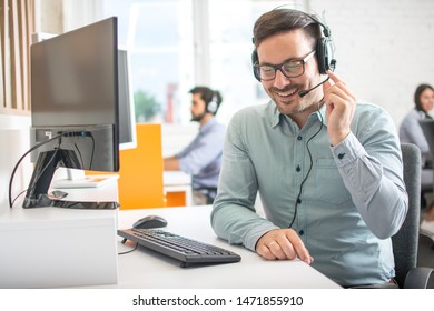 Friendly Customer Support Agent Man With Headset Talking With Client In Call Centre