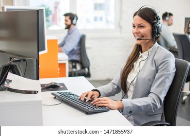 Friendly customer support service operator with headset working in call centre.