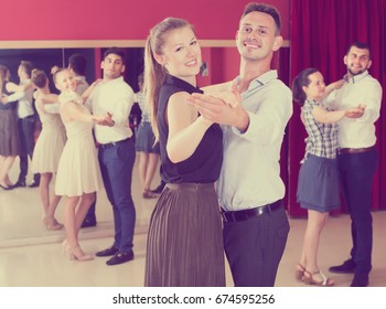 Friendly Dancing Couples Enjoying Foxtrot In Dance Studio