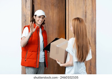 Friendly Delivery Man Waving At Customer While Handing Over Parcel In Doorway. Perfect For Topics On Home Delivery Service, Online Shopping, And Customer Satisfaction. - Powered by Shutterstock