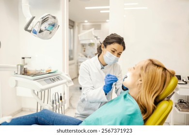Friendly dentist examining patient's teeth at dentist office.