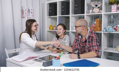 Friendly Doctor Writes Out A Teenager After His Illness And Hugs Her Goodbye. Father And Daughter Teen Discharged After An Illness In The Doctor's Office.