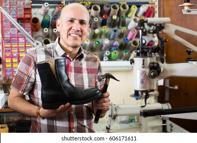 Friendly elderly smiling specialist fixing heel taps of shoes on machine - Powered by Shutterstock