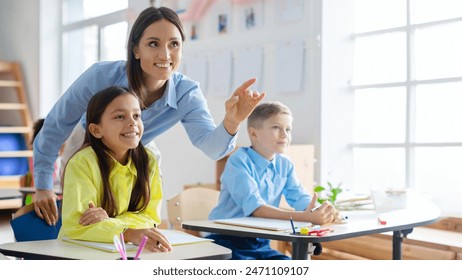 Friendly European female teacher standing among engaged pupils, pointing at blackboard and explaining, creating vibrant learning atmosphere - Powered by Shutterstock