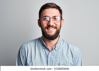 Friendly Face Portrait Of An Authentic Caucasian Bearded Man With Glasses Of Toothy Smiling Dressed Casual Against A White Wall Isolated