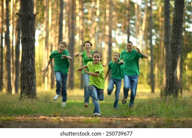 Friendly Family Running Together In Autumn Park