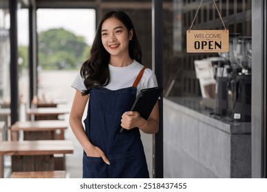 Friendly Female Barista Standing at Cafe Entrance Welcoming Customers with a Smile - Powered by Shutterstock