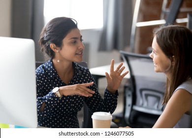 Дружелюбные женщины-коллеги, имеющие хорошие отношения, приятная беседа на рабочем месте во время кофе-брейка, улыбающаяся молодая женщина слушает разговорчивую коллегу, обсуждают новый проект, разговаривают в офисе