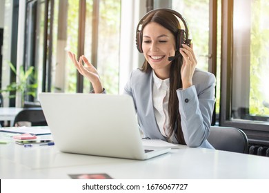 Friendly female customer support operator with headset talking with a client at office