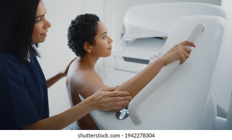 Friendly Female Doctor Explains the Mammogram Procedure to a Topless Latin Female Patient with Curly Hair Undergoing Mammography Scan. Healthy Female Does Cancer Prevention Routine in Hospital Room.