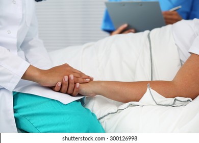 Friendly Female Doctor Hands Holding Patient Hand Lying In Bed For Encouragement, Empathy, Cheering And Support While Medical Examination. Bad News Lessening, Compassion, Trust And Ethics Concept