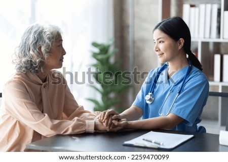 Friendly female doctor supporting an elderly lady.