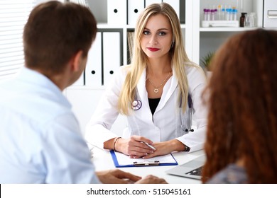 Friendly Female Family Doctor Listen Carefully Young Couple In Office. Motherhood And Child Delivery, New Life Or Abortion, Therapeutist Reception Service, Physical, Hospital And Clinic Concept