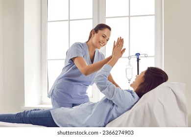 Friendly female gynecologist doctor giving high five to her pregnant woman patient lying on the couch in medical clinic and receiving IV drip infusion and vitamin therapy. Healthy pregnancy concept. - Powered by Shutterstock