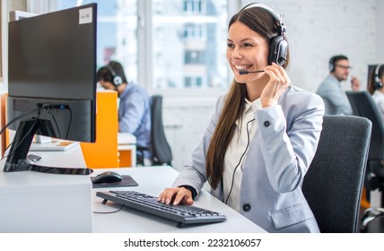 Friendly female helpline operator in call center. Young woman working in call center and holding microphone on headset with hand. - Shutterstock ID 2232106057