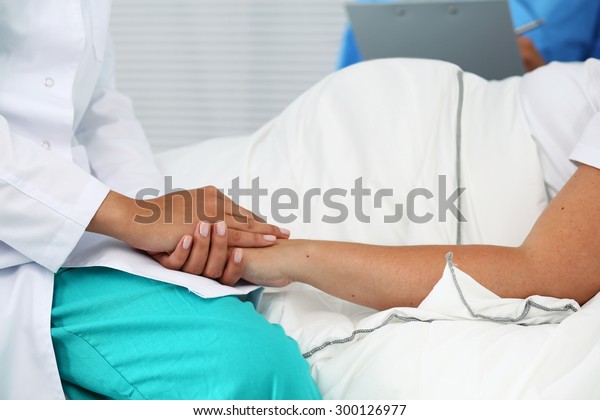 Las manos amigables de las médicas sujetando la mano de la mujer embarazada en la cama para animar, empatizar, animar y apoyar durante el examen médico. Nuevo concepto de vida del aborto