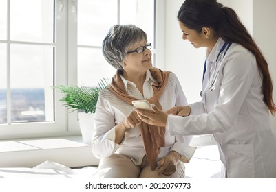 Friendly female nurse teaches an older woman to use modern health programs on her mobile phone. Caring doctor talks to an elderly patient. Concept of medicine and modern technology.