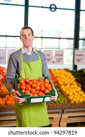 A Friendly Grocery Store Owner With A Box Of Ripe Tomatoes